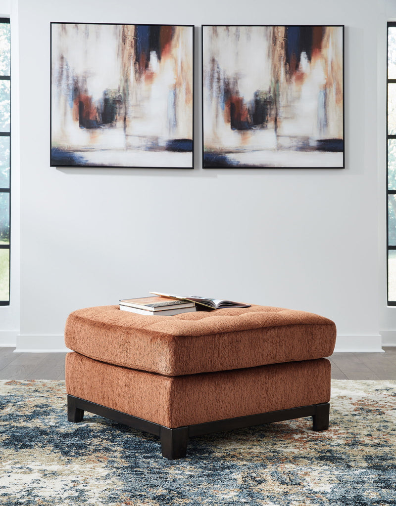 Ashley® Laylabrook oversized plush square accent ottoman in spice with dark wood trim, showcasing soft fabric and sturdy wooden legs.