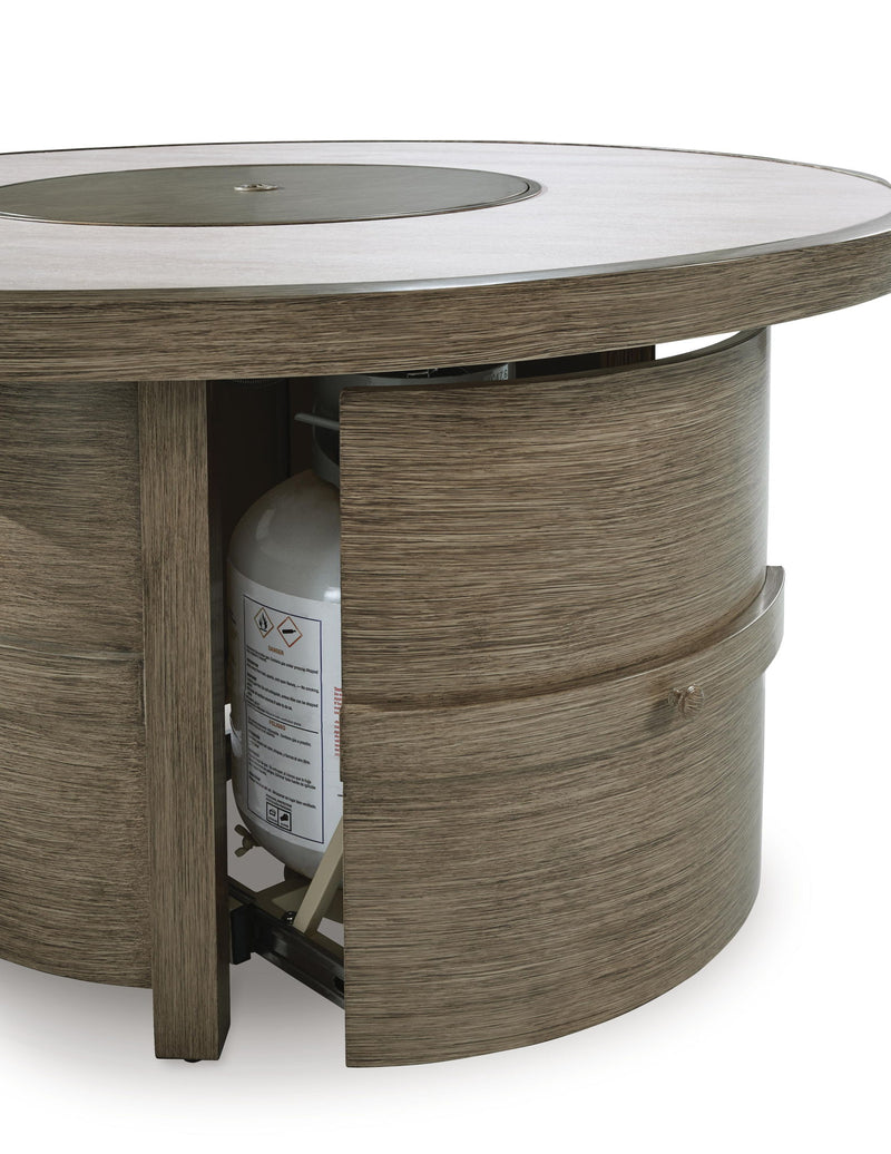 Beige round fire pit table from Rainier Ranch by Signature Design, featuring a smooth surface and sturdy metal base.