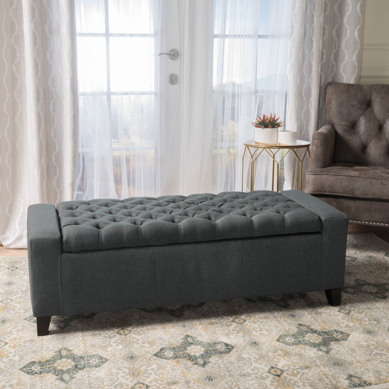Dark gray Noble House storage ottoman with tufted top, featuring a contemporary design and functional storage space.