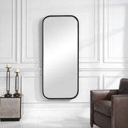 Black tall iron wall mirror by Uttermost with a sleek, minimalist frame, perfect for modern interior decor.