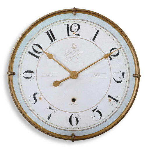Uttermost Torriana wall clock with a gold finish, round design, and minimalist style, hanging on a wall.