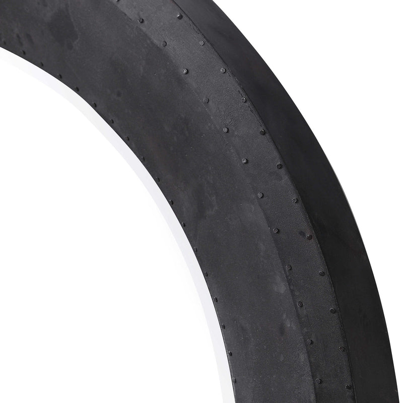 Round industrial wall mirror in black with a sleek metal frame, designed for modern home decor by Uttermost.