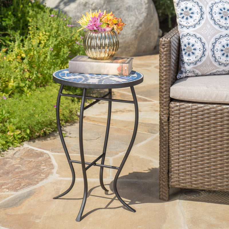 Outdoor round side table with mosaic-style top and curved iron legs in blue and matte black, by Noble House.