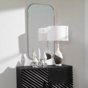 Uttermost Taft wall mirror with a sleek, modern frame hanging on a wall, showcasing its reflective glass surface.