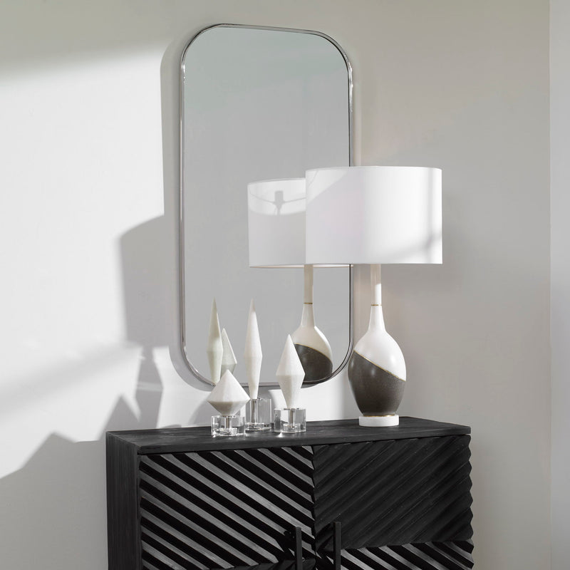 Uttermost Taft wall mirror with a sleek, modern frame hanging on a wall, showcasing its reflective glass surface.