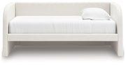 Upholstered Signature Design by Ashley Arloster daybed with plush cushions and wooden frame, ideal for guest or relaxation space.
