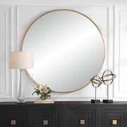 Uttermost Junius round wall mirror with a sleek frame, hanging on a wall, reflecting light and room decor.