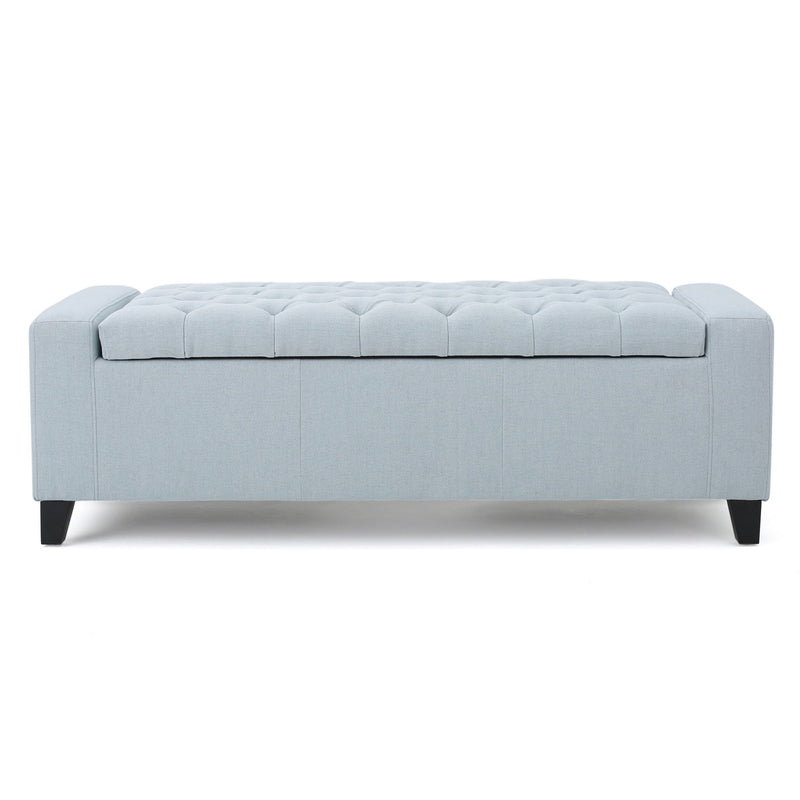 Noble House Guernsey storage ottoman with tufted top, beige fabric, and sturdy wooden legs, serving as both seat and storage.