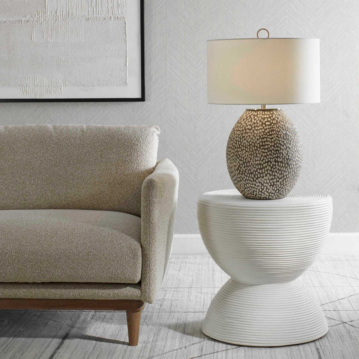 Uttermost Cyprien gray and white table lamp with a modern, sleek design and smooth ceramic base on a neutral surface.