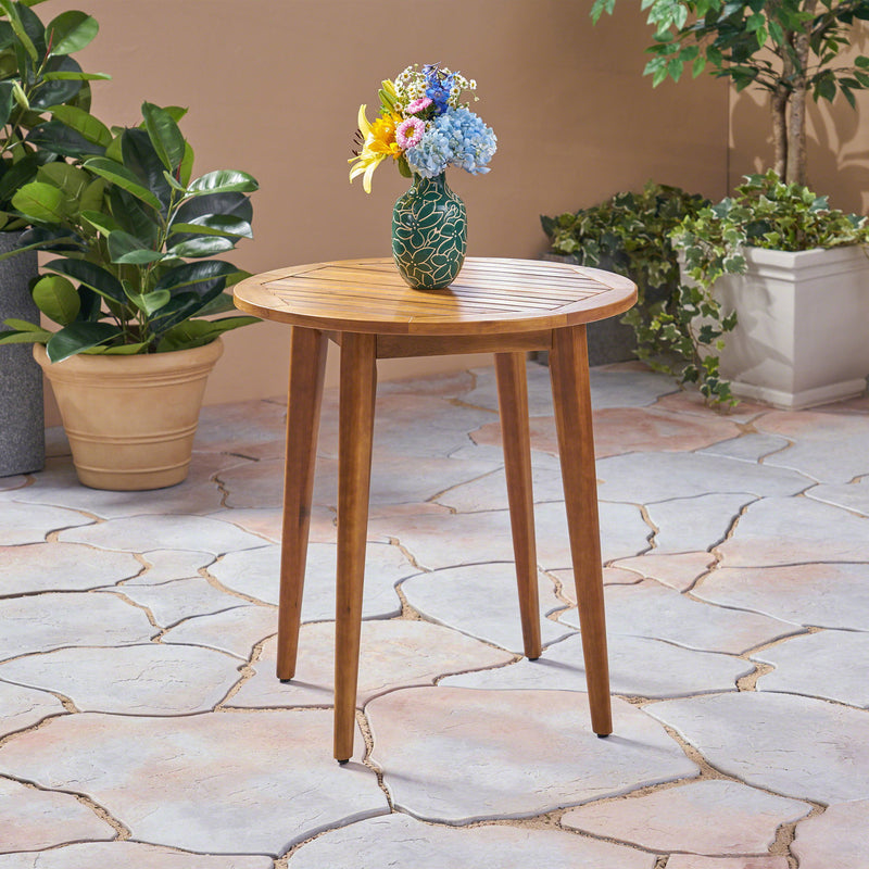 Noble House Stamford outdoor bistro table with teak surface, water-resistant design, ideal for patio or garden seating.