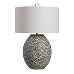 Uttermost Cyprien gray and white table lamp with a sleek, modern design and a cylindrical base on a wooden surface.