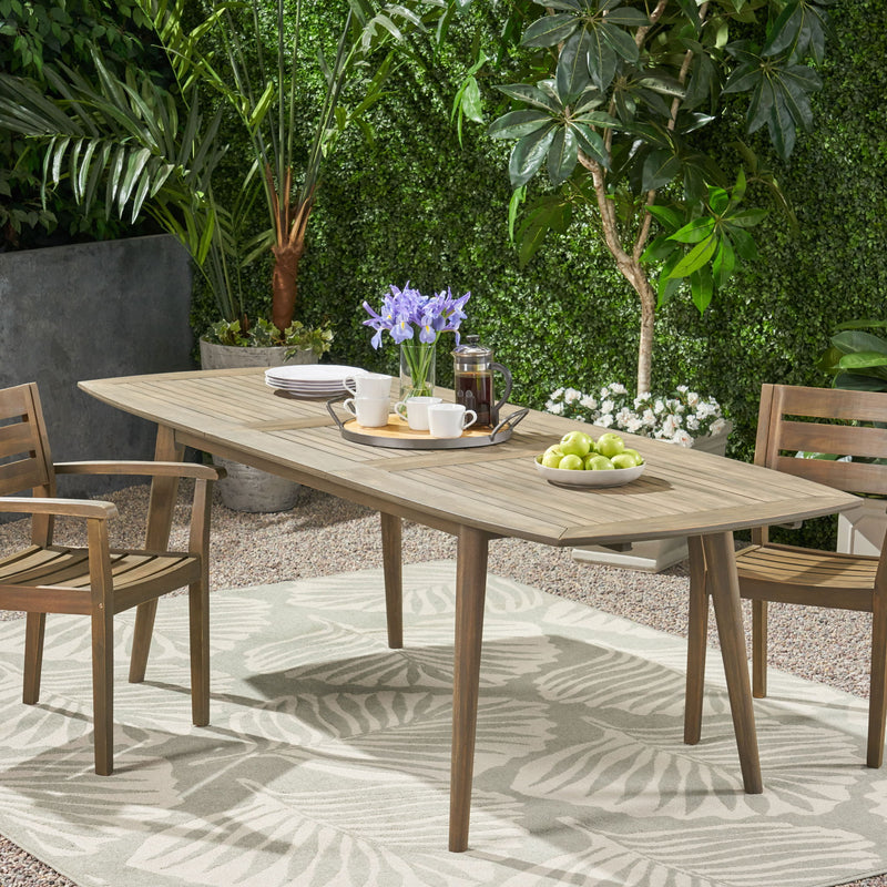 Noble House Placidity outdoor expandable dining table with slatted tabletop and tapered legs, suitable for patio or garden dining.