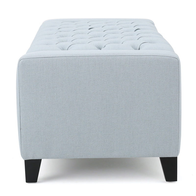 Noble House Guernsey storage ottoman with tufted top, beige fabric, and sturdy wooden legs, serving as a versatile accent piece.