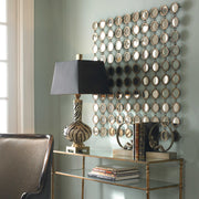 Uttermost Dinuba wall mirror with antique silver champagne finish, decorative frame, hanging on a wall in a stylish interior setting.