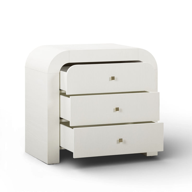 TOV Furniture Hump bedside chest with two drawers and wooden finish, placed beside a bed in a modern bedroom setting.
