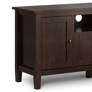 Handcrafted Warm Shaker TV media stand by Simpli-Home with wood finish, featuring open shelves and storage compartments.