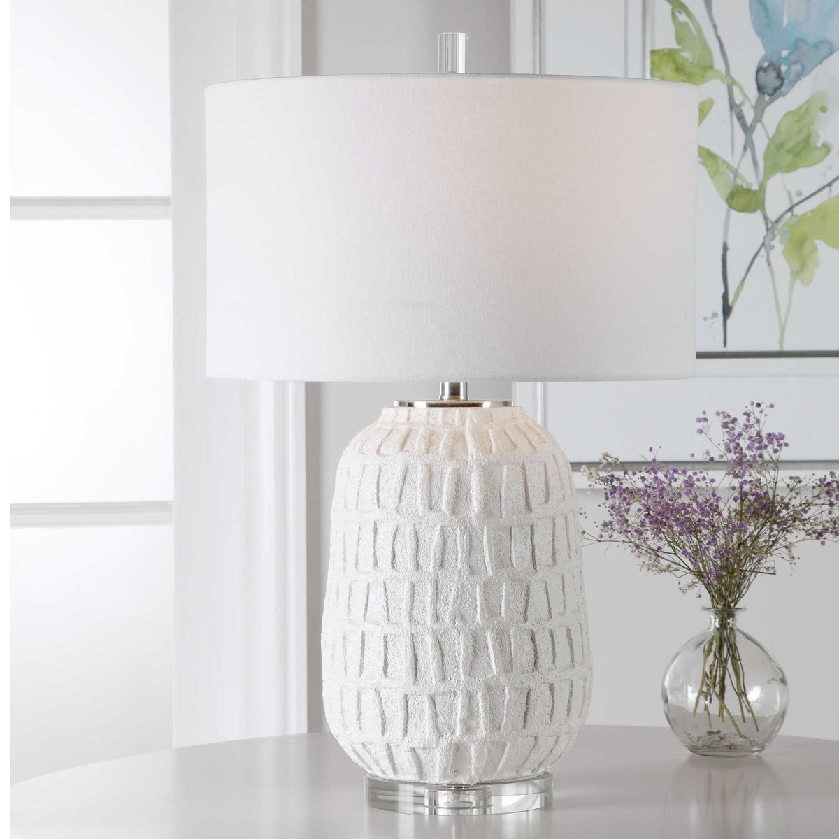 White textured Caelina table lamp by Uttermost with a modern design, featuring a cylindrical base and fabric shade.