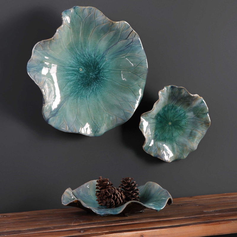 Set of three blue ceramic flower wall decor pieces by Uttermost, featuring detailed floral designs for home decoration.