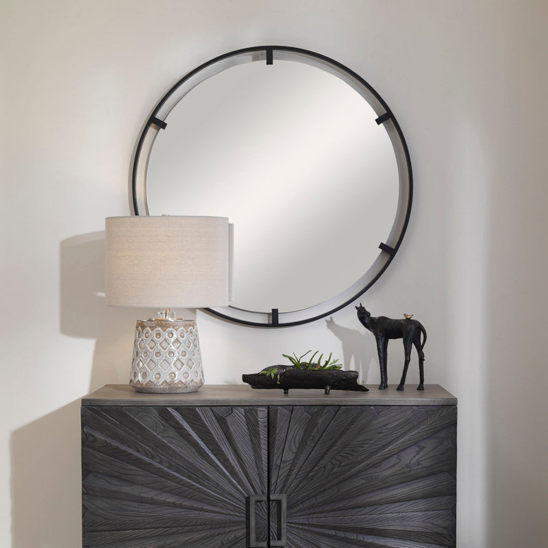 Black round iron accent mirror by Uttermost with a sleek, minimalist design, mounted on a wall.