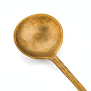 Anuja large brass serving spoon from TOV Furniture's flatware set, featuring a polished, flat handle and wide spoon bowl.