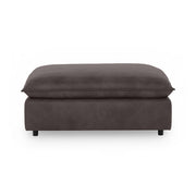 Classic Home Caplan upholstered ottoman with a plush fabric surface and wooden legs, perfect as a footrest or accent piece.