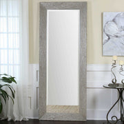 Large silver floor mirror by Uttermost with a sleek, modern frame reflecting surrounding space in a contemporary setting.
