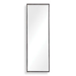 Uttermost Callan black leaner mirror with sleek frame, standing tall against a wall in a modern interior setting.
