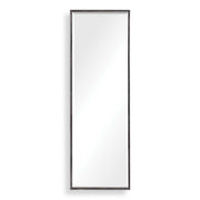 Uttermost Callan black leaner mirror with sleek frame, standing tall against a wall in a modern interior setting.