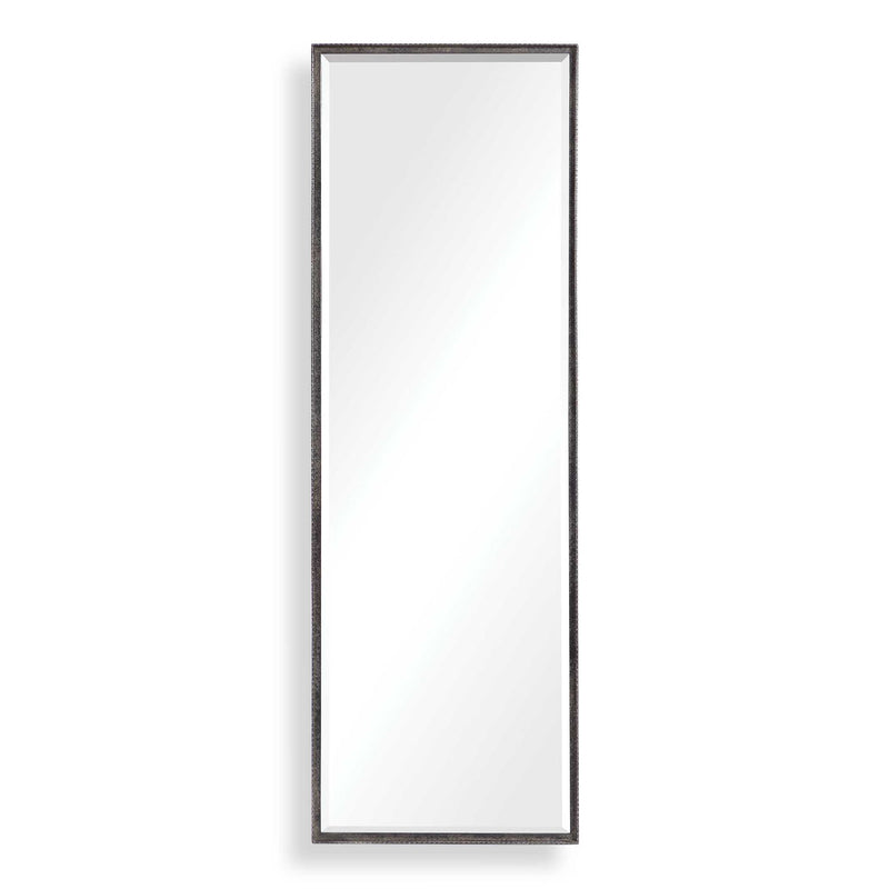 Uttermost Callan black leaner mirror with sleek frame, standing tall against a wall in a modern interior setting.