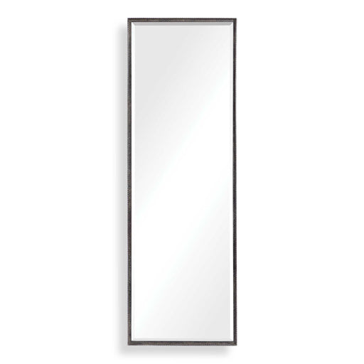 Uttermost Callan black leaner mirror with sleek frame, standing tall against a wall in a modern interior setting.