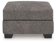 Olten Benchcraft® accent ottoman with plush fabric and wooden legs, serving as a stylish, versatile footrest or small table.