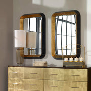 Uttermost Niva metallic gold wall mirror with a round frame, hanging on a modern interior wall.