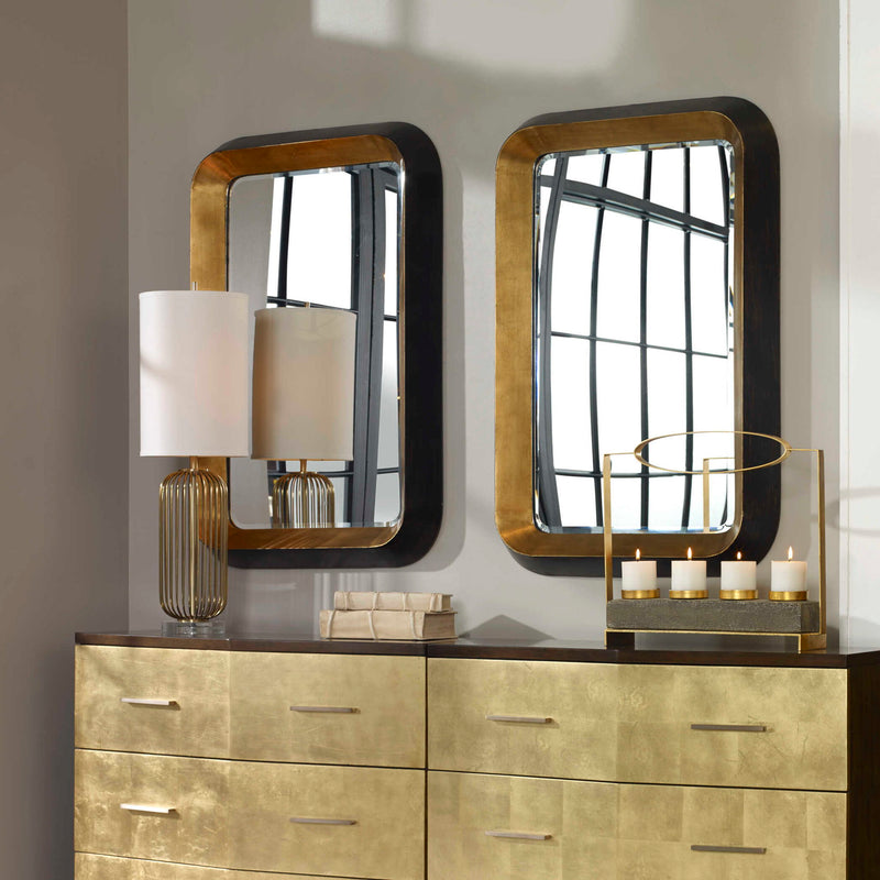 Uttermost Niva metallic gold wall mirror with a round frame, hanging on a modern interior wall.