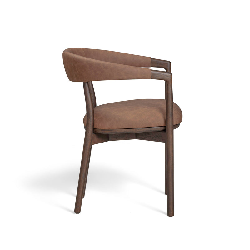 Vina vegan leather dining arm chair by TOV Furniture with sleek modern design and cushioned seat in natural light setting.