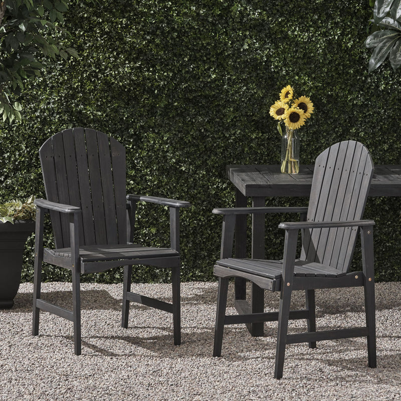 Set of two Noble House outdoor weather-resistant acacia wood Adirondack dining chairs on patio.