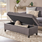 Noble House Juliana storage ottoman with birch wood legs, cushioned top, and fabric upholstery in a stylish living room setting