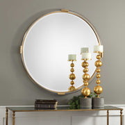 Round gold wall mirror by Uttermost, featuring a sleek gold frame and reflective glass surface for modern interior decor.