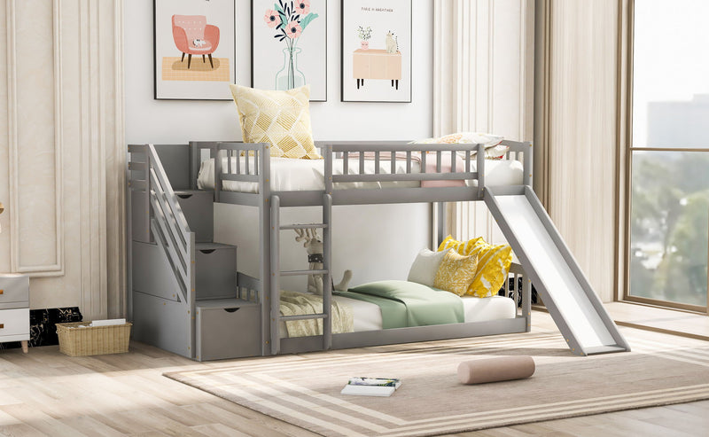 Gray DreamHaus twin over twin bunk bed with stairway, two drawers, and slide, featuring safety railings and a sturdy frame.