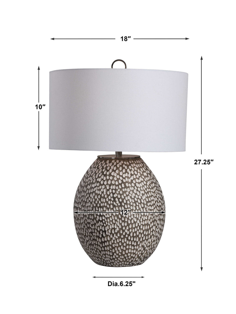 Uttermost Cyprien gray and white table lamp with a modern design and cylindrical base on a wooden surface.