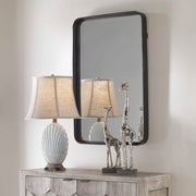 Black Croften vanity mirror by Uttermost with a sleek, modern design and a round reflective surface.