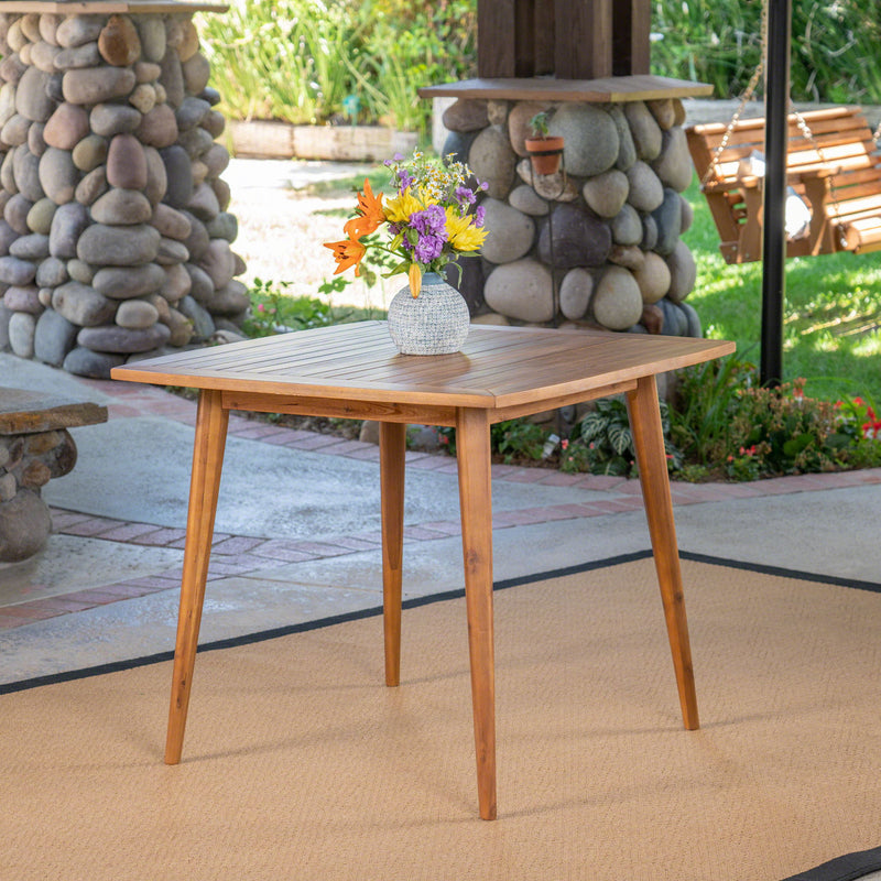 Modern indoor square dining table with acacia wood surface and toothpick leg design by Noble House