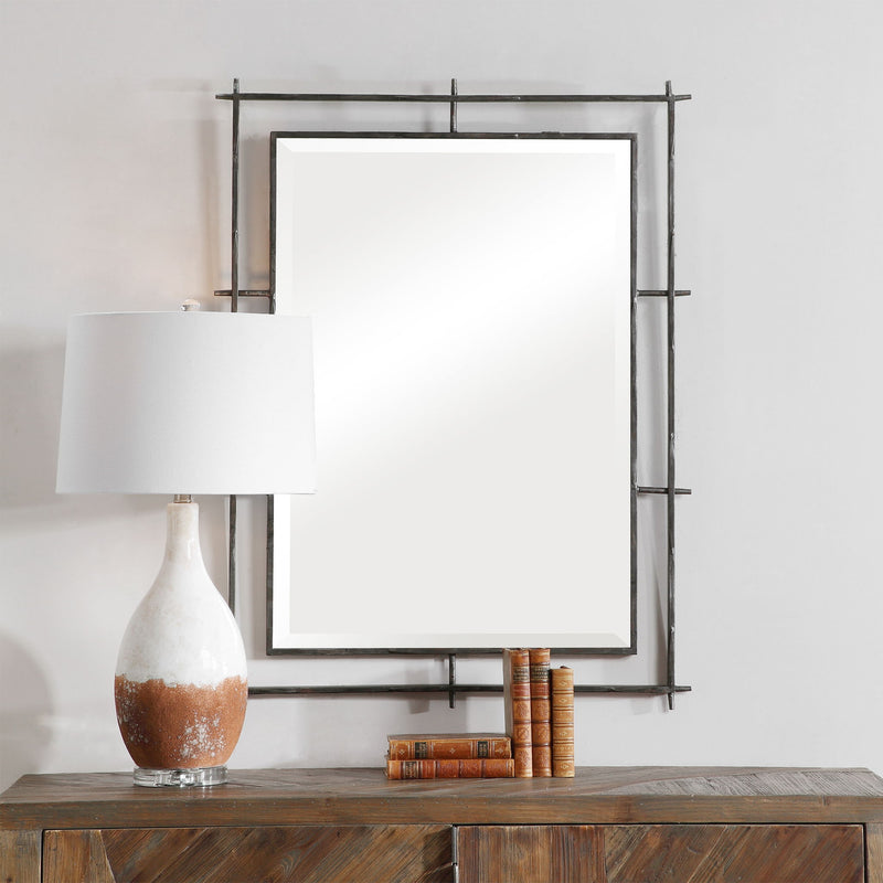 Uttermost Ironworks industrial black wall mirror with metal frame, modern design, reflecting a stylish interior space.