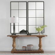 Black iron window mirror by Uttermost featuring a grid-style accent design, mounted on a wall showing reflections.