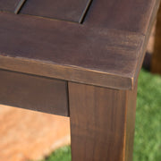 Dark brown acacia wood outdoor dining table with slatted top, perfect for patio or garden dining spaces.