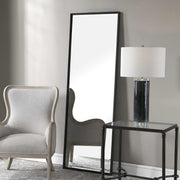 Uttermost Callan Leaner Mirror in black with a sleek, modern frame, standing tall against a neutral background.