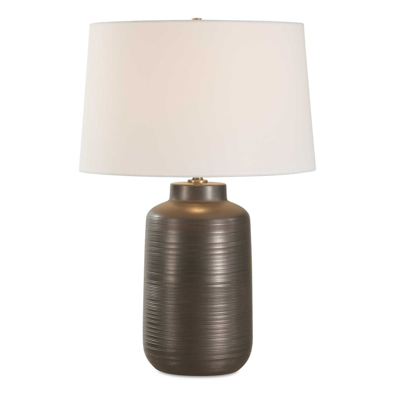 Uttermost Calderone bronze table lamp with a sleek, modern design and a matching bronze finish, shown on a contemporary table.