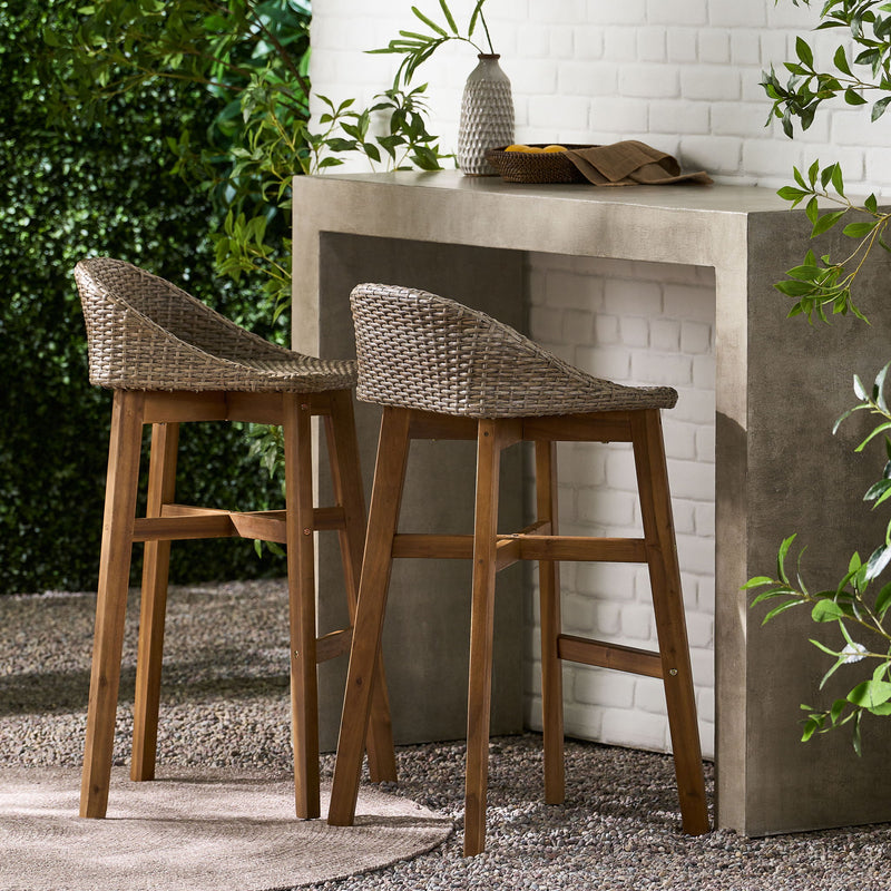 Noble House Beeson outdoor wicker and acacia wood barstool set in brown, water-resistant, with four stylish barstools arranged outside.