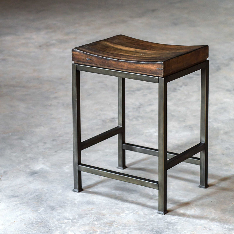 Industrial Beck counter height bar stool by Uttermost featuring metal frame and wooden seat, suitable for kitchen or bar area.