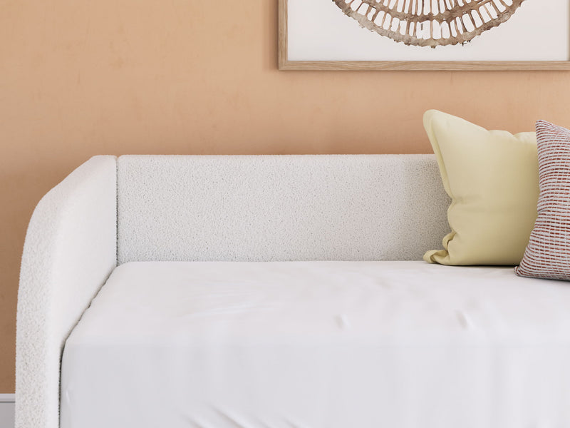 Upholstered Signature Design by Ashley® Arloster day bed with plush fabric, wooden frame, and decorative pillows in a cozy living space.