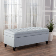 Noble House Juliana storage ottoman with beige fabric upholstery and birch wood legs, serving as a stylish storage and seating piece.